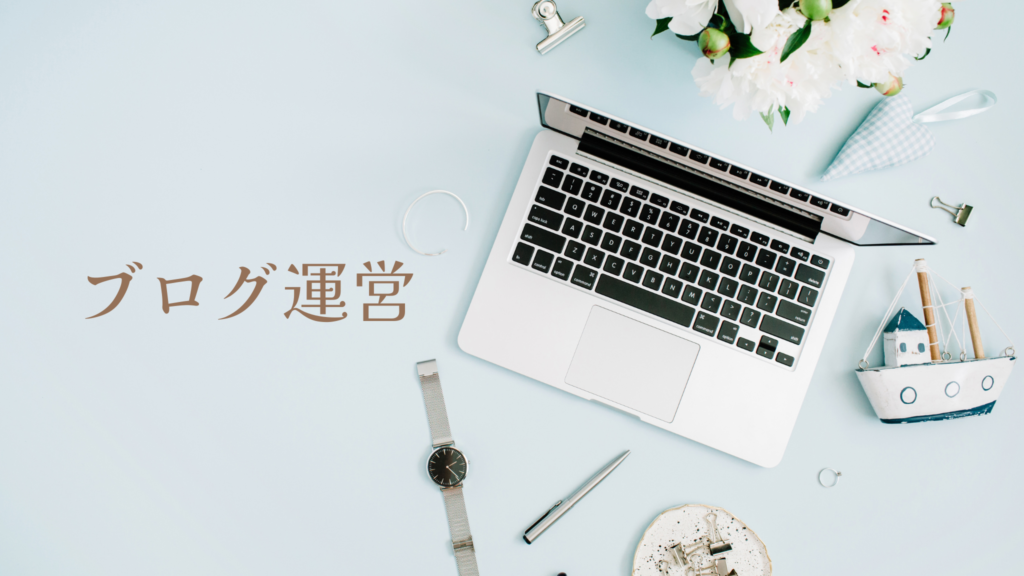 テーブルの上にパソコン、腕時計、船のおもちゃ、造花がセンスよく置かれている